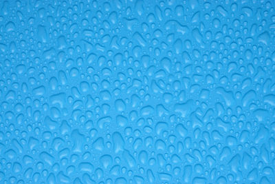 Full frame shot of water drops on blue surface