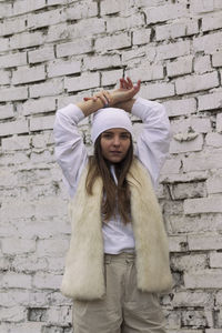 Full length of woman standing against brick wall