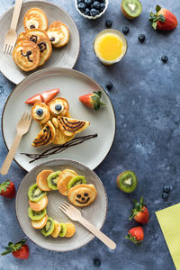 Pancakes in the shapes of critters, served with fruit and juice for kids.