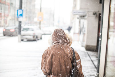 Rear view of woman walking on road during winter