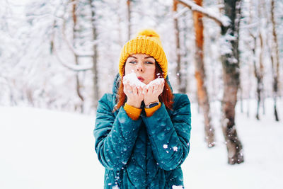 Portrait of smiling young woman standing in snow