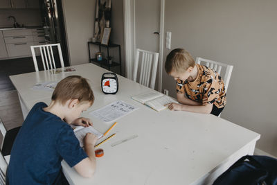 Schoolboys doing homework according to clock