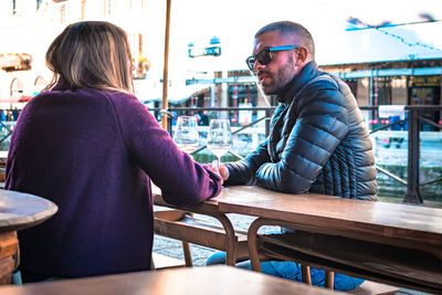 Couple holding wineglasses on table talking while sitting at outdoor cafe