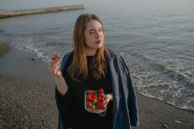 Portrait of young woman standing at beach