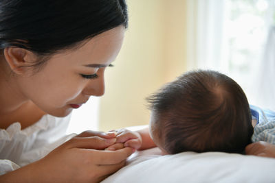 Close-up of mother looking at son lying on bed