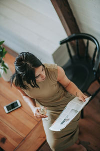 Woman reading magazine while having wine at home