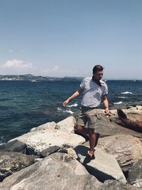 Man standing on rock against sea at beach