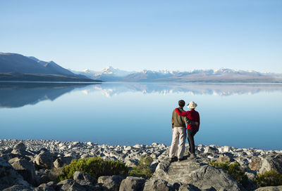 Rear view of man looking at lake against sky