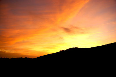 Scenic view of silhouette mountains against orange sky