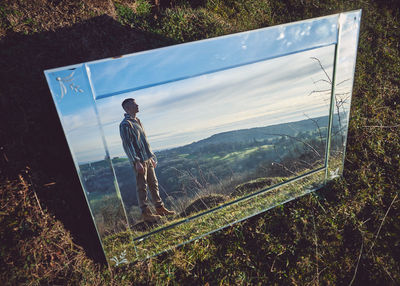 Young man and landscape reflecting on mirror 