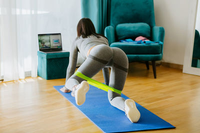 Rear view of woman sitting on chair at home