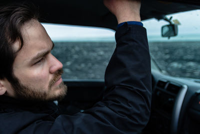 Close-up of man in car looking away