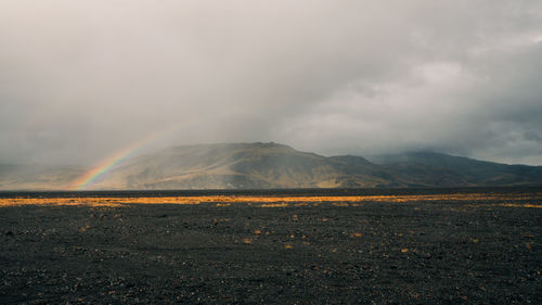 Scenic view of rainbow over mountain and land against sky