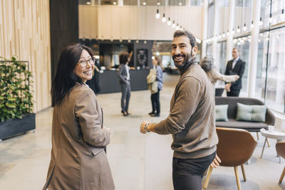 Portrait of happy male and female delegates walking in lobby at convention center
