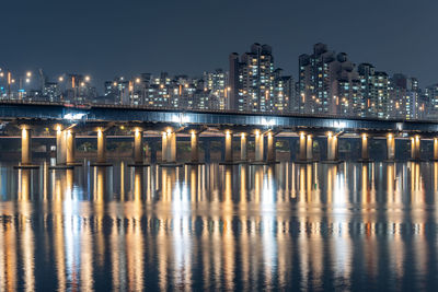 Illuminated bridge over river against sky at night