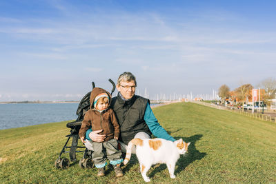 Portrait of grandfather and granddaughter with cat on grass