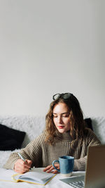 Young woman using mobile phone while sitting at home