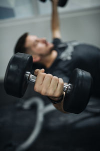 Close-up image young man lifting weights in a gym.