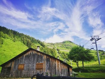 House on field by trees against sky