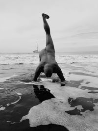 Full length of shirtless man on beach against sky