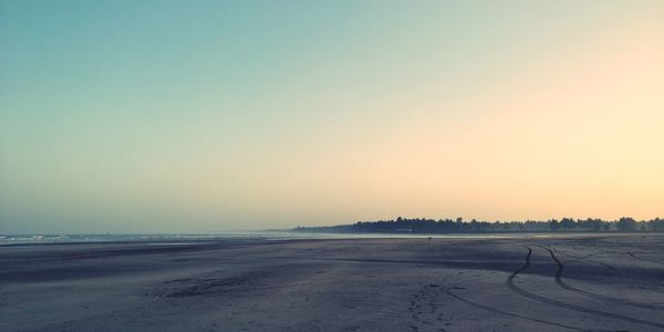 Scenic view of beach against clear sky during sunset
