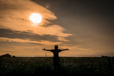 Silhouette man standing on field against sky during sunset