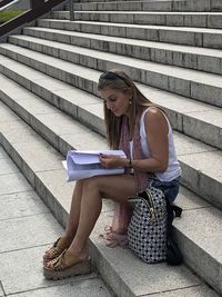 Woman using mobile phone while sitting on staircase