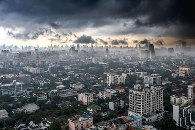 Aerial view of cityscape against cloudy sky