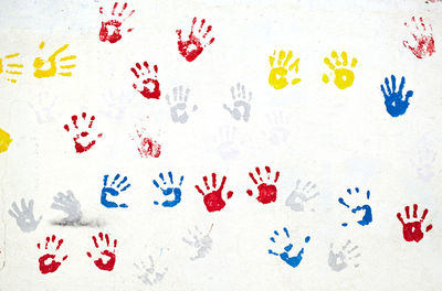 Close-up of colorful handprints on white wall