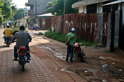 Rear view of people riding bicycle on street