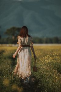 Rear view of woman standing on field against sky