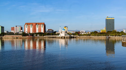 Reflection of buildings in lake against blue sky