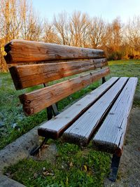 Wooden bench on field against sky