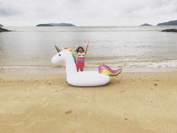 Happy girl with inflatable ring standing at beach