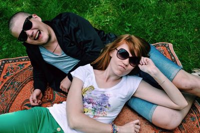 Portrait of friends in sunglasses relaxing on field