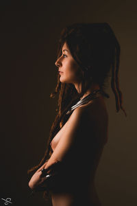 Side view of a young woman against black background