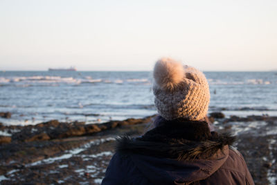 Rear view of man standing at beach against clear sky