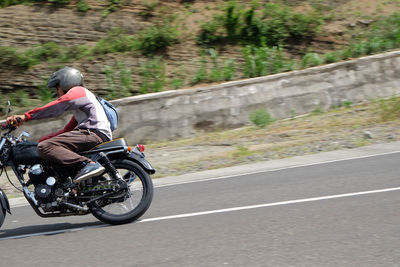 Rear view of man riding motorcycle on road