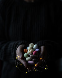 Close-up of hand holding a chocolat egg over black background