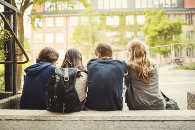 Rear view of teenagers sitting on steps outdoors