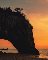 Rock formation in sea against sky during sunset