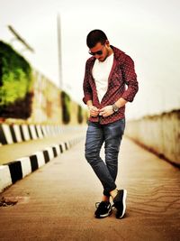 Young man looking away while standing against wall