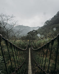 Footbridge over mountains against sky