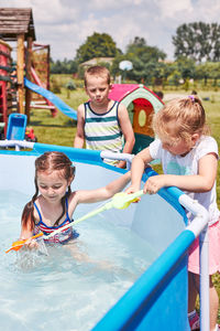 Children playing in a pool with fishing rod toy in a home garden. kids having fun playing together