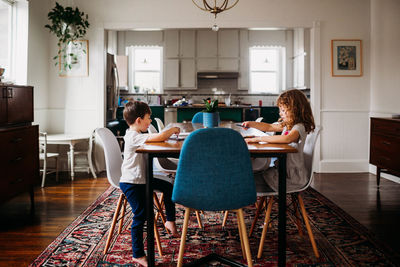 Young brother and sister sitting at dining table coloring together