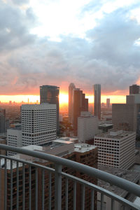 Modern buildings in city against sky during sunset