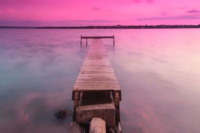 Pier over lake against sky during sunset