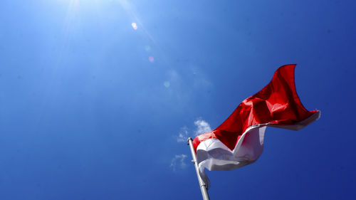 Low angle view of flag against blue sky