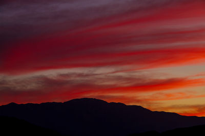 Low angle view of silhouette mountains against romantic sky