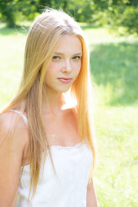 Portrait of teenage girl standing on field during sunny day